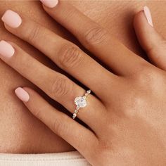 a woman's hand with a diamond ring on her left hand and pink manicured nails