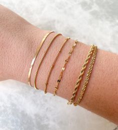 Dainty stainless steel bracelets that can be layered / stacked are ideal for mixing and matching! Combine your favorite gold link chains to create a seamless look. Plus, they are tarnish resistant and waterproof; you can wear them to the pool or gym and they won't tarnish! Herringbone (2.5 mm): 7" +1.5" extender (Clasp & Jump Ring Excluded) Box: 6.75” + 2" extender Satellite: 6" + 1.5" extender Rope (2.5 mm): 6.25" + 2" extender Dainty Gold Bracelet, Bracelet Box, Gold Link Chain, Gold Link, Gold Bracelets, Jewelry Lookbook, Minimalist Bracelet, Crown Jewels, Letter Charms