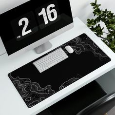 a computer desk with a black and white mouse pad next to a keyboard on top of it