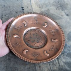 a hand holding a decorative metal plate with stars and moon designs on the rim,