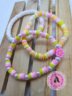 two bracelets are sitting on top of a piece of wood with beads and flowers