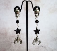 If you like your jewellery with a bit of the goth/grunge aesthetic then these bat and black star earrings with skull earposts could be just what you need! The skull stud posts are stainless steel and have stainless steel backs, below them hangs black faceted glass beads, black stars and at the bottom a silverplated bat charm. They hang approx 6cm or just under 2.5" in total and are lightweight and comfortable to wear. These skull earrings are great for goth girls, or boys, who love jewellery wit Black Piercings For Halloween Gift, Black Dangle Metal Piercings, Black Metal Dangle Piercings, Black Skull Jewelry Grunge Style, Black Skull Shaped Grunge Jewelry, Black Skull Grunge Jewelry, Adjustable Black Skull-shaped Earrings, Adjustable Black Skull Earrings, Punk Style Star-shaped Metal Earrings