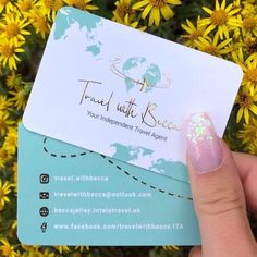 a person holding up a business card in front of yellow flowers with a world map on it