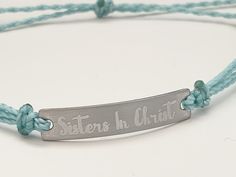 "This is an engraved waterproof bracelet, It is shown with an engraved brushed stainless steel bar and mint straps. You can choose your metal color and strap color. The bar will be engraved with \"Sisters in Christ\". You can choose back side engraving for personalization during checkout. Please let us know if you have any questions! The back can also be engraved. CHARACTER LIMIT- 14 characters per side Each item is made-to-order, which gives our pieces a unique meaning that is specific and spec Adjustable Stainless Steel Bracelets With Engraved Text, Adjustable Stainless Steel Bracelet With Engraved Text, Adjustable Engraved Name Bracelet For Friendship, Adjustable Name Bracelet With Engraved Text As Gift, Adjustable Silver Name Bracelet With Engraved Text, Silver Name Bracelet Laser Engraved For Gift, Inspirational Engraved Adjustable Name Bracelet, Silver Laser Engraved Name Bracelet For Gift, Inspirational Engraved Name Bracelet, Adjustable