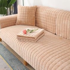 a couch that has some blankets on it next to a potted plant in the corner