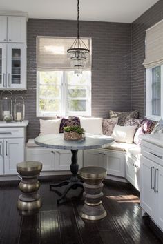 a kitchen with white cabinets and wood flooring is pictured in this image, the table has two stools on it