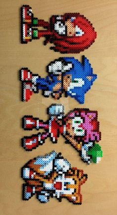 some pixel art made to look like mario and sonic characters on a wooden table top