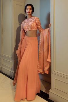 Peach lehenga in solid base. Paired with full churidar sleeves padded blouse with all over wildflower embroidery and embroidered border dupatta.
Components: 3
Pattern: Embroidery
Type Of Work: Floral Thread Work, Glass, Sequin, Beads
Neckline: Round Neck
Sleeve Type: Full Sleeves
Fabric: Blouse: Net
Lehenga: Pure Georgette
Dupatta: Silk Organza
Color: Peach
Other Details: 

Model height: 5 ft 8 inches, wearing size XS
Closure: 
Blouse : Back hook
Lehenga : Side hook with zipper
Length of lehenga Peach Net Lehenga, Thread Work Blouse, Churidar Sleeves, Wildflower Embroidery, Peach Lehenga, Wedding Fits, Simple Lehenga, Full Sleeve Blouse, Georgette Dupatta