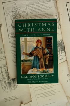 the book christmas with anne by l m montgomery is laying on top of papers