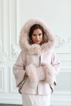 a woman in a fur coat and dress with her hands on her hips, posing for the camera