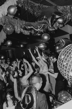 black and white photograph of people dancing at a party with disco balls hanging from the ceiling