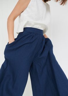 "The Clementine palazzo is the right choice for warmer days when you want to give a romantic touch to your look. The pants boast a cropped hem, in-seam pockets and a flattering gathered skirt-like high waist with an elastic band in the back. IMPORTANT: The Clementine pants have been altered to have a gathered waist instead of the pleated one. If you own a pair with pleated front, note that the pants you will receive will be different. This garment is true to size, and we recommend choosing the s Wide Linen Pants, Navy Blue Trousers, Linen Culottes, Pants Linen, Womens Trousers, Summer Linen Dresses, Fleece Leggings, Blue Trousers, Pinafore Dress