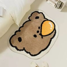 a brown teddy bear rug sitting on top of a white floor next to slippers