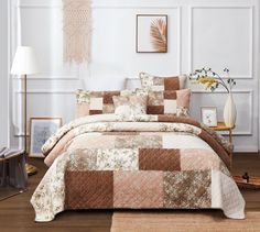 a bed with a brown and white quilt on top of it next to a lamp