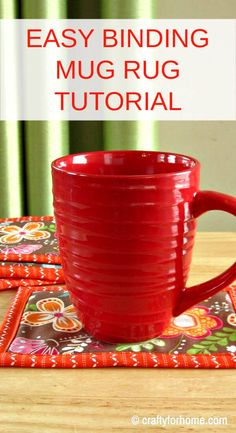 a red mug sitting on top of a wooden table next to two placemats