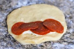 a pizza dough with two slices of pepperoni on it