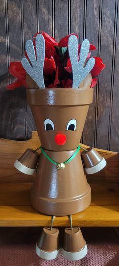 a brown flower pot with red flowers in it and reindeer antlers sticking out of the top