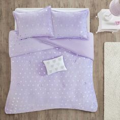 a bed with purple and white polka dots on the comforter, next to a rug