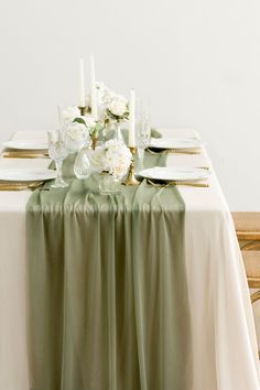 the table is set with white flowers and place settings