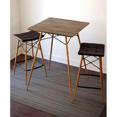 a table and two stools on a carpeted floor in front of a white wall