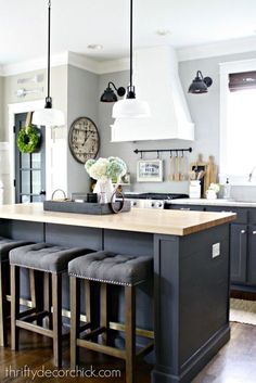 a kitchen island with four stools in front of it and a clock on the wall