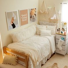 a bedroom with white bedding and pictures on the wall