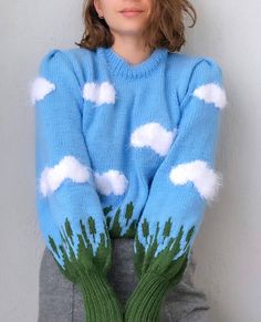 a woman wearing a blue sweater with white clouds on it