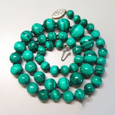 On offer is this high quality Vintage natural emerald green Malachite graduated bead necklace. This beautiful vintage necklace consists of genuine rich emerald blue green round beads that is hand-knotted with silk cord and finished with a sterling silver gold filigree clasp with a safety latch that opens and closes tightly. These Malachite gems are highly polished and very lustrous. The glossy Malachite beads range in size from 1/2 inch diameter at the front to 6/16 inch diameter at the clasp. T Green Single Strand Necklace For Formal Occasions, Single Strand Emerald Necklace For Formal Occasions, Classic Green Gemstone Necklace, Classic Green Gemstone Beads Necklace, Formal Green Necklace With Gemstone Beads, Classic Green Single Strand Necklace, Vintage Green Emerald Necklace For Formal Occasions, Formal Green Single Strand Beaded Necklace, Emerald Beaded Necklaces With Natural Stones