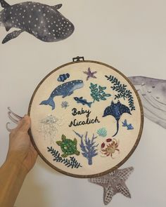 someone is holding up a cross stitch project with dolphins and other sea creatures on it