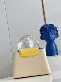 a white purse sitting on top of a table next to a blue vase with flowers