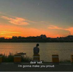 a person sitting on a bench looking out over the water with a sunset in the background