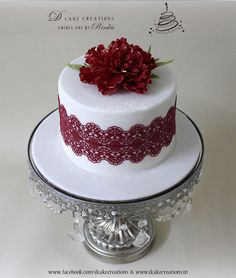 a white cake with red lace and flowers on top