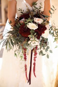 a bride holding a bouquet of flowers and greenery