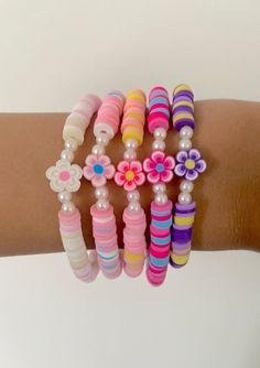 a woman's arm with several bracelets and flowers on it, all in different colors