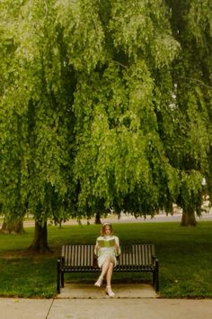 a woman sitting on a bench under a tree