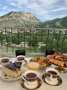 a table topped with plates and cups of coffee next to dessert on top of a table