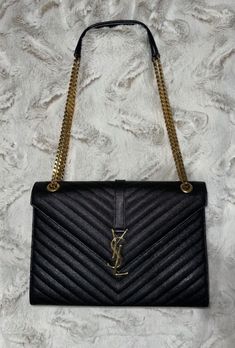 TIMELESS SOPHISTICATION  YVES SAINT LAURENT ENVELOPE LARGE BAG IN MATELASSÉ GRAIN DE POUDRE EMBOSSED LEATHER CHEVRON PATTERN. FRONT FLAP WITH MAGNETIC SNAP CLOSURE AND GOLD METAL YSL INITIALS, LEATHER AND CHAIN STRAP CAN BE WORN MULTIPLE WAYS. • 100% CALFSKIN LEATHER • DIMENSIONS: 31 X 22 X 7,5 CM / 12.2 X 8.6 X 2.9 INCHES • DOUBLED STRAP DROP: 30 CM / 11.8 INCHES • STRAP DROP: 52 CM / 20.4 INCHES • VERSATILE STRAP CAN BE WORN ON THE    SHOULDER OR CROSSBODY Saint Laurent Envelope Bag, Cute Handbags, Envelope Bag, Large Bag, Chevron Pattern, Embossed Leather, Chain Strap, Ysl Bag, Snap Closure