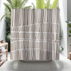 a bathroom with a shower curtain that has stripes on it and palm trees in the background