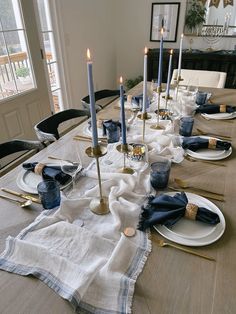 a dining table set with place settings and napkins, candles on the plates in front of them