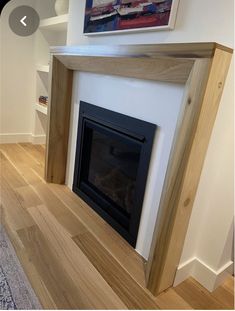 an empty room with a fire place in the center and hardwood flooring on the other side