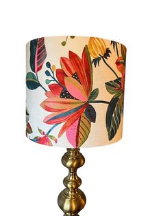 a lamp that is sitting on top of a wooden table with a flower print lampshade