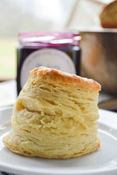 a piece of bread sitting on top of a white plate next to a jar of jam