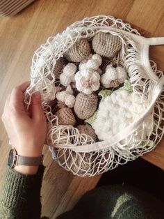 a person is holding a bag full of crocheted items on a wooden table