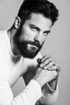 a man with a beard and white shirt is posing for a photo in black and white