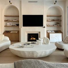 a living room filled with furniture and a flat screen tv mounted on the wall above a fire place