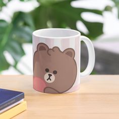 a coffee mug with a bear on it sitting on a table next to some books