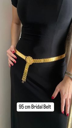 a woman wearing a black dress and gold belt with a golden key on the waist