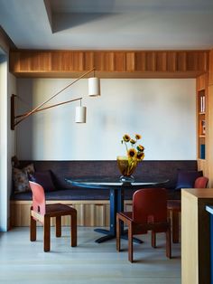 a dining room table and chairs with flowers in vase on the center, along with bookshelves