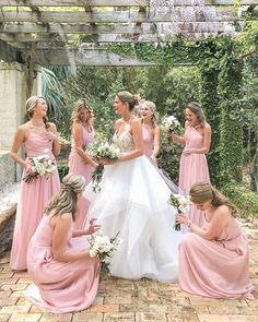 a group of women in pink dresses standing around each other and one woman holding a bouquet