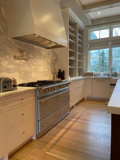 a large kitchen with white cabinets and stainless steel stove top oven, built in shelving